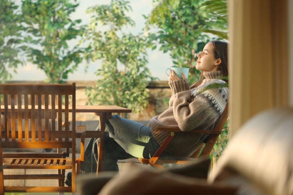 Frau auf einer Hausterrasse, die Kaffee trinkt und entspannt