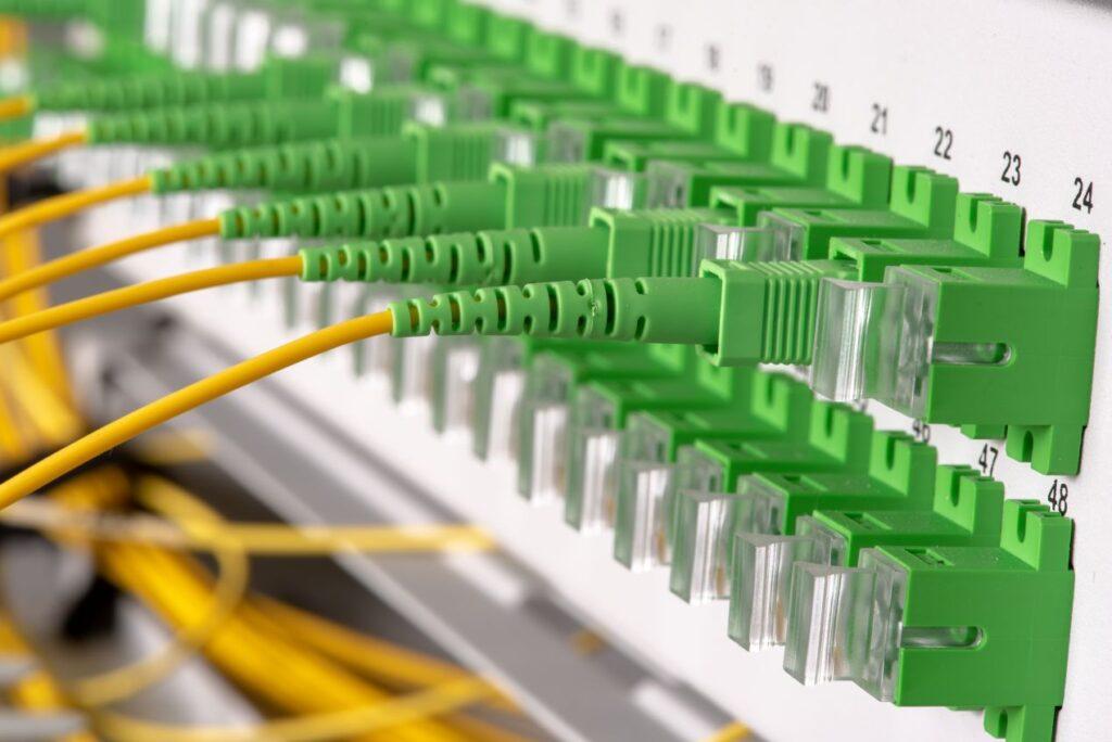 Grünes FTTH Zubehör mit gelben Glasfaserkabeln an einem Patchpanel in der Netzwerktechnik